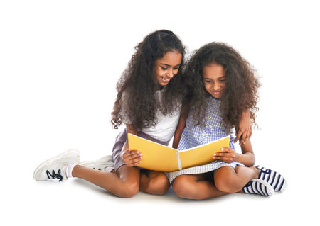 Cute African-American girls with book on white backgroundの写真素材