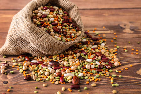 Sack bag with assortment of legumes on wooden tableの写真素材