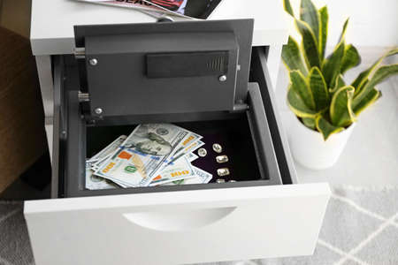 Small modern safe with money in cabinet drawerの写真素材