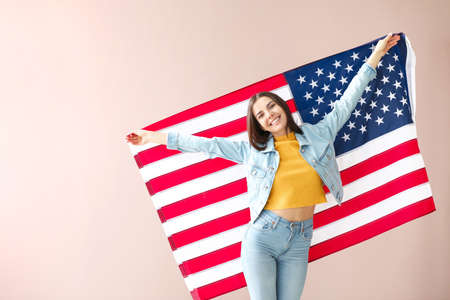Happy young woman with national flag of USA on color background