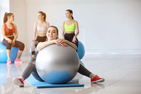 Young sporty woman with fitball in gym