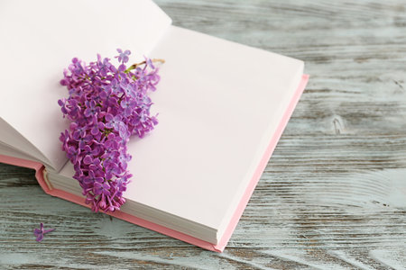 Book with beautiful lilac flowers on wooden tableの写真素材