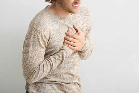 Young man suffering from chest pain on white background