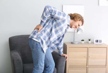 Young man suffering from back pain at home