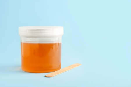 Container with sugaring paste for epilation on color background