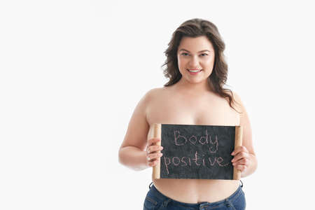 Plus size woman holding board with text BODY POSITIVE on white backgroundの写真素材