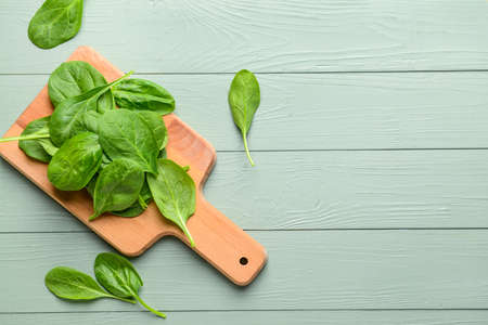 Wooden board with fresh spinach on tableの写真素材