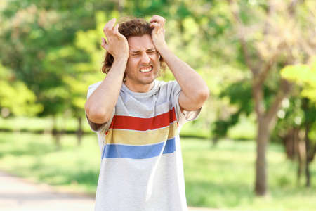 Young man suffering from headache outdoors