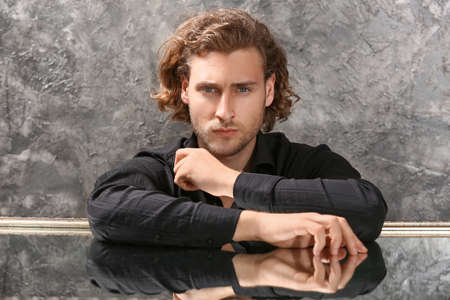 Stylish young man in fashionable clothes sitting at tableの写真素材