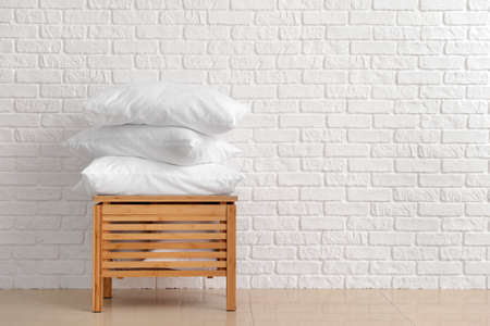 Soft pillows on wooden box against white brick wallの写真素材