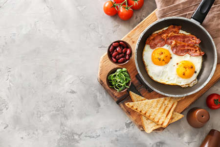 Traditional English breakfast with fried eggs, bacon, beans and toasts on tableの写真素材