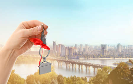 Female hand with key from house in modern cityの写真素材