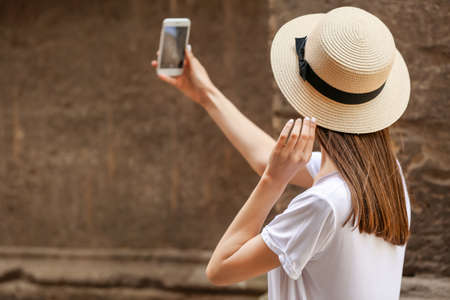 Young woman with mobile phone taking selfie outdoorsの写真素材