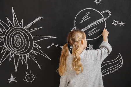 Little girl drawing space on dark wallの写真素材