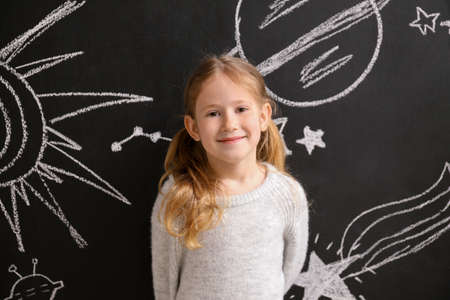 Little girl near dark wall with drawn spaceの写真素材