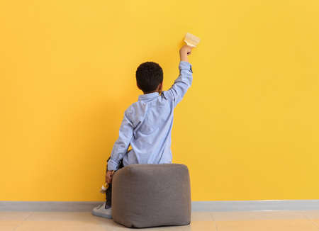 Cute African-American boy painting wall in roomの写真素材