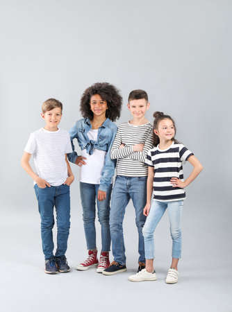 Stylish children in jeans on gray background