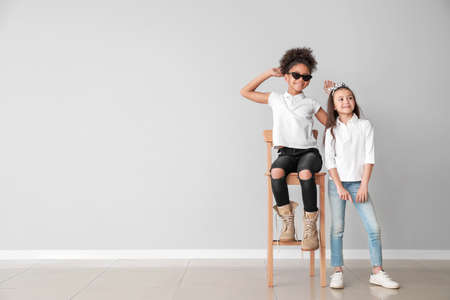 Stylish girls in jeans near gray wallの写真素材