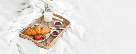 Tray with tasty breakfast on bed