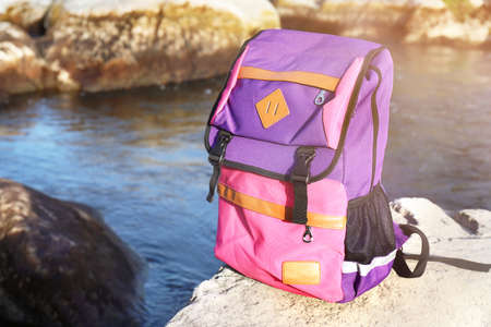 Tourist's backpack on rock near mountain streamの写真素材