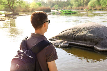Male tourist near river with rocks