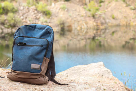Tourist's backpack on rock near mountain lake
