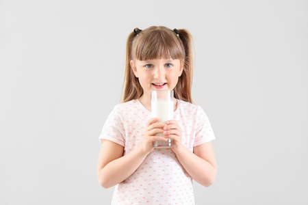 Cute little girl with glass of milk on white backgroundの写真素材