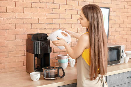 Beautiful woman using coffee machine in kitchenの写真素材