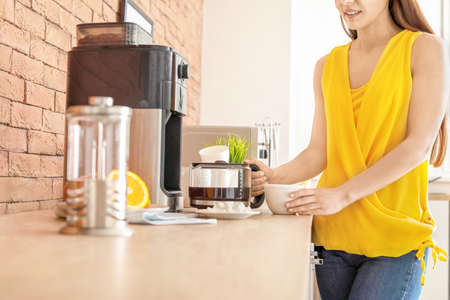 Beautiful woman using coffee machine in kitchen
