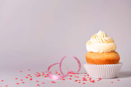 Tasty Birthday cupcake on gray background