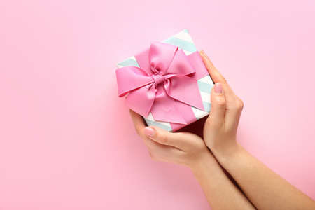 Female hands with beautiful gift box on color backgroundの写真素材