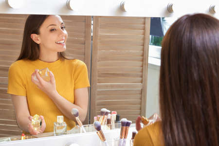 Young woman near mirror in makeup roomの写真素材