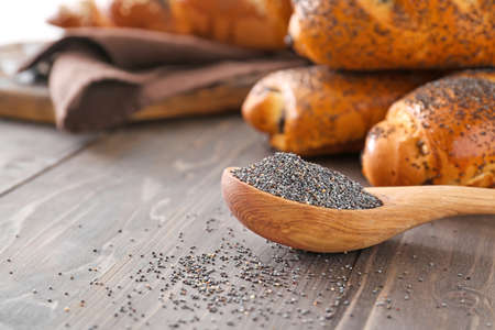 Spoon with poppy seeds on wooden tableの写真素材