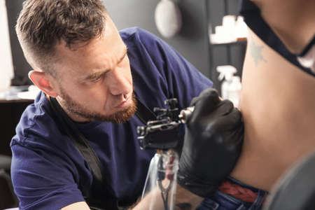 Professional artist making tattoo in salonの写真素材