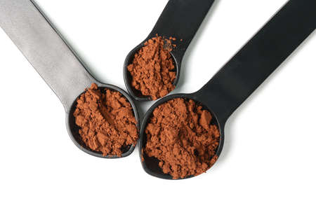 Spoons with cocoa powder on white background