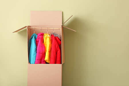 Wardrobe box with clothes on color background