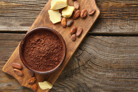 Bowl with cocoa powder on wooden background