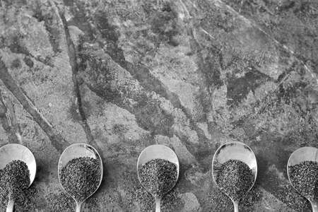 Spoons with poppy seeds on grunge background