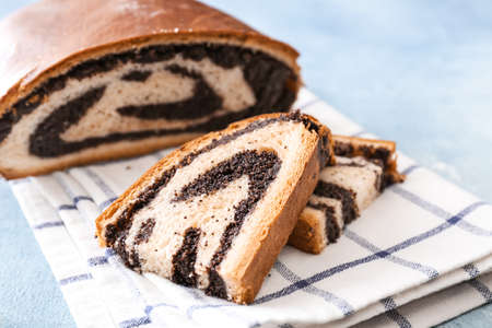 Tasty bun with poppy seeds on table