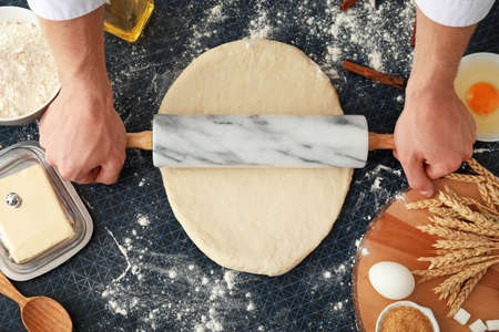 Man rolling out dough on kitchen table