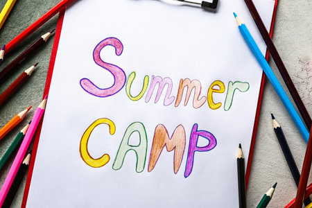 Sheet of paper with text SUMMER CAMP and pencils on gray backgroundの写真素材