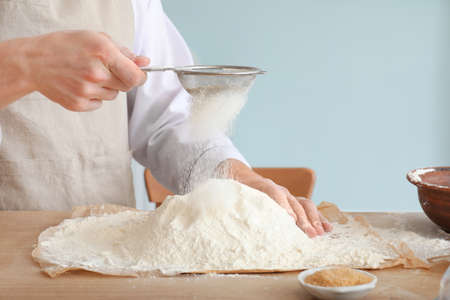 Male chef sieving flour in kitchenの写真素材