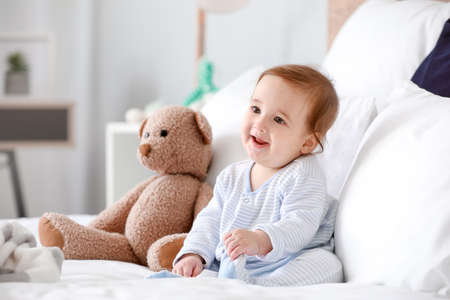 Portrait of adorable baby boy with toy on bed at homeの写真素材