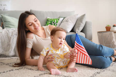 Mother and her little baby with national flag of USA at home