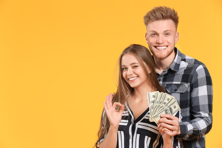 Happy couple with money on color backgroundの写真素材