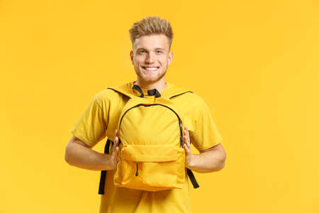 Portrait of handsome young man with backpack on color backgroundの写真素材