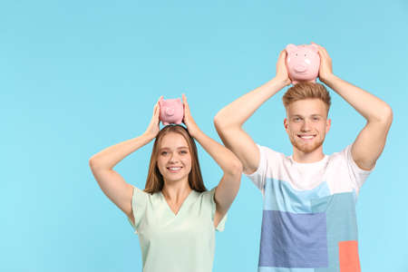 Happy couple with piggy banks on color backgroundの写真素材