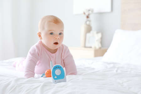 Modern baby monitor on bed with little childの写真素材