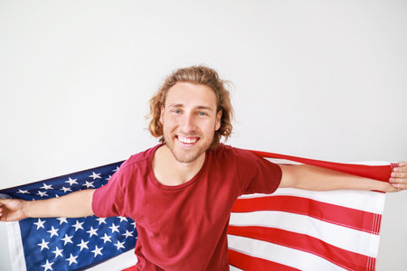 Happy young man with USA flag on white background. Independence Day celebrationの写真素材