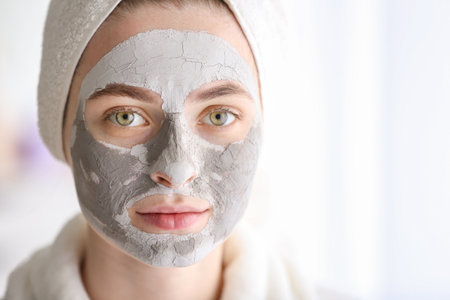 Young woman with clay mask at homeの写真素材